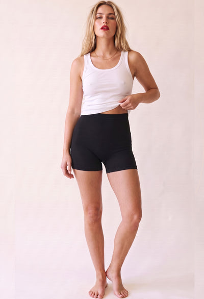 Model wearing black cotton rich boxer shorts with a white ribbed tank, full-length front view